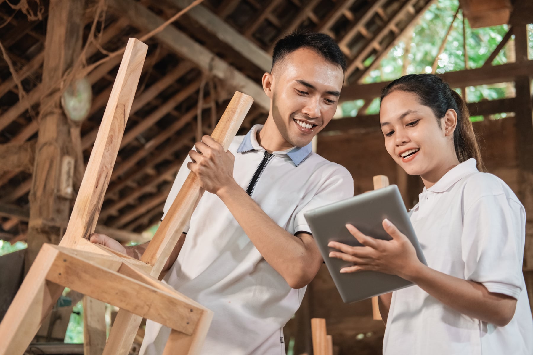 Young Entrepreneur Holding a Tablet and Showing Furniture Designs to a Carpenter